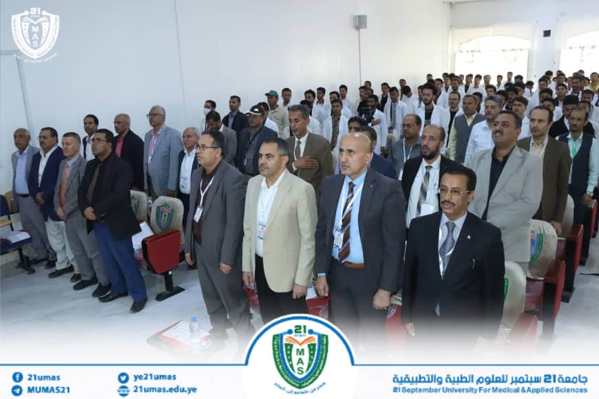 Group of formally dressed men standing in a bright lecture hall during a university event at 21 September University for Medical & Applied Sciences.