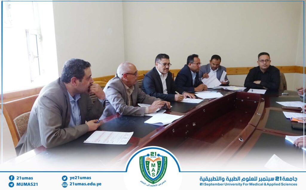 Group of men in a formal meeting around a conference table at 21 September University for Medical & Applied Sciences.