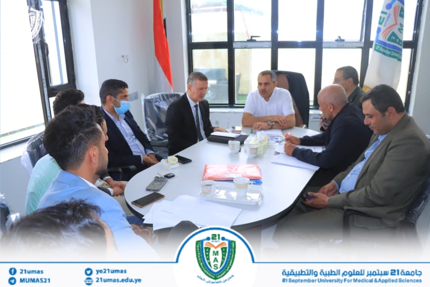 Group of professionals in a bright office seated around a conference table, discussing papers and notes.