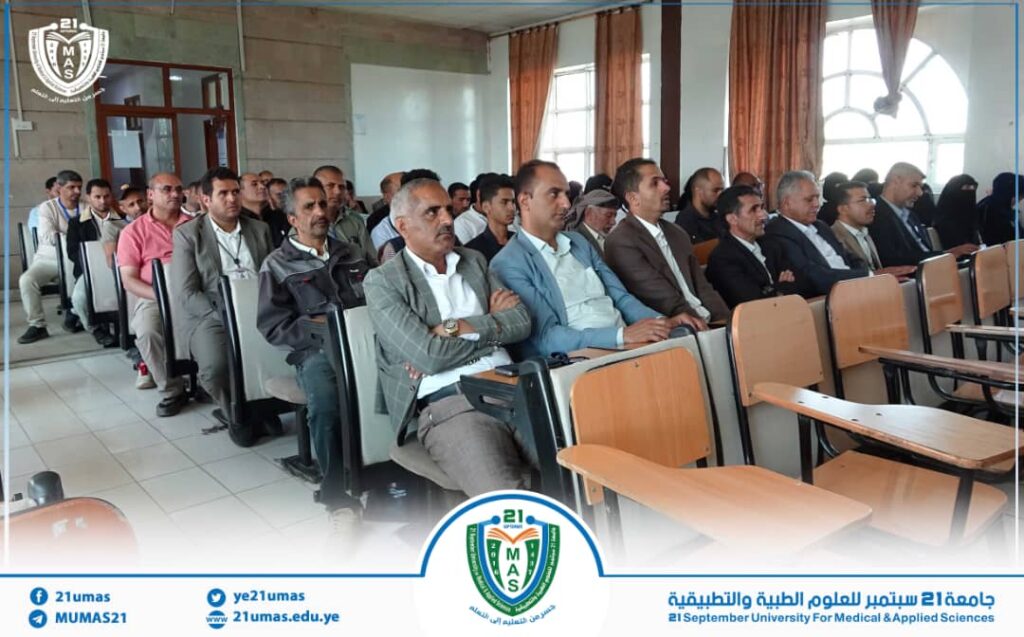 Audience seated in a lecture hall listening to a presentation, with a university logo and banner at the bottom showing '21 September University for Medical & Applied Sciences'.