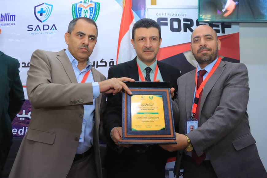 Three men in suits pose with a framed award during a ceremony, badges on lanyards visible behind them.