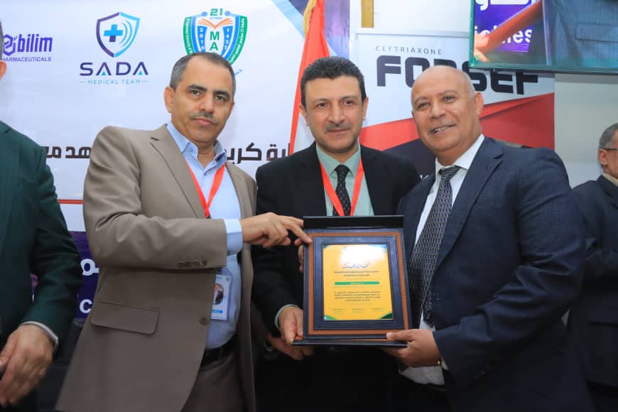 Three men in suits pose on stage as one hands a framed plaque to another at an award ceremony.