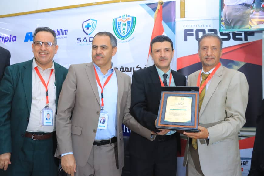 Four men in business attire posing at an awards event, with one holding a framed certificate as they smile for the camera.