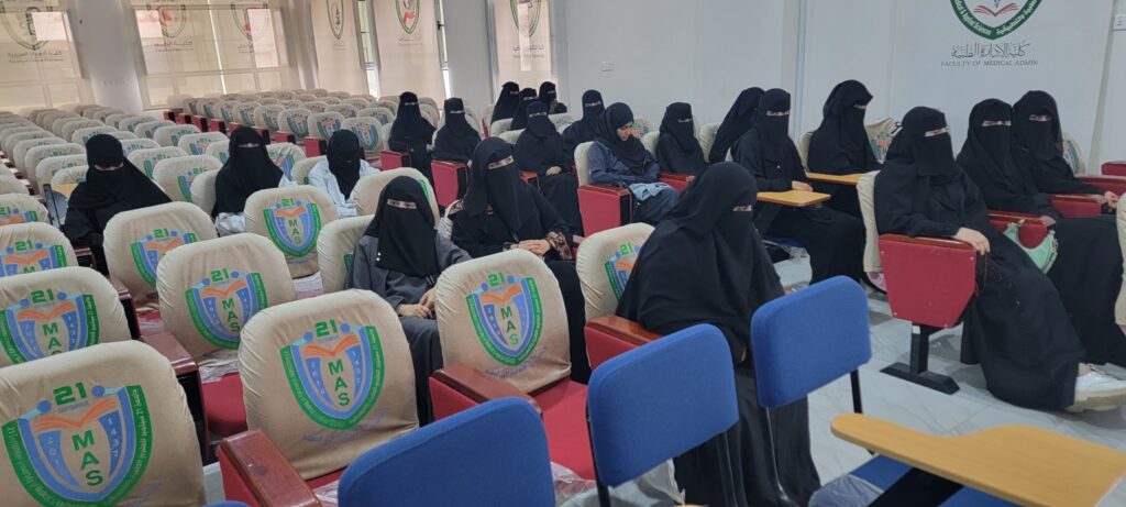 Group of women wearing black abayas and niqabs seated in a university lecture hall, attending a class.