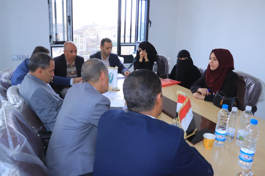 Group of professionals seated around a conference table in a bright room, discussing documents.