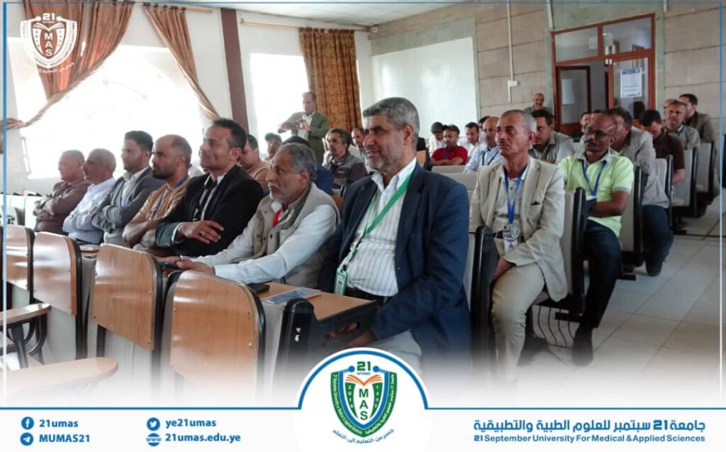 1001171679 - جامعة 21 سبتمبر Conference room full of men seated in rows, attending a university seminar or lecture.