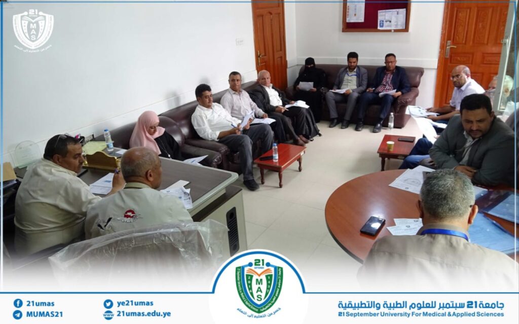 Group of university staff seated on couches in a meeting room, reviewing papers and discussing documents.
