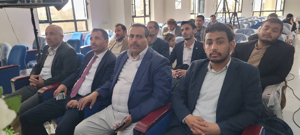 Group of men in suits seated in a conference hall, facing forward during a presentation