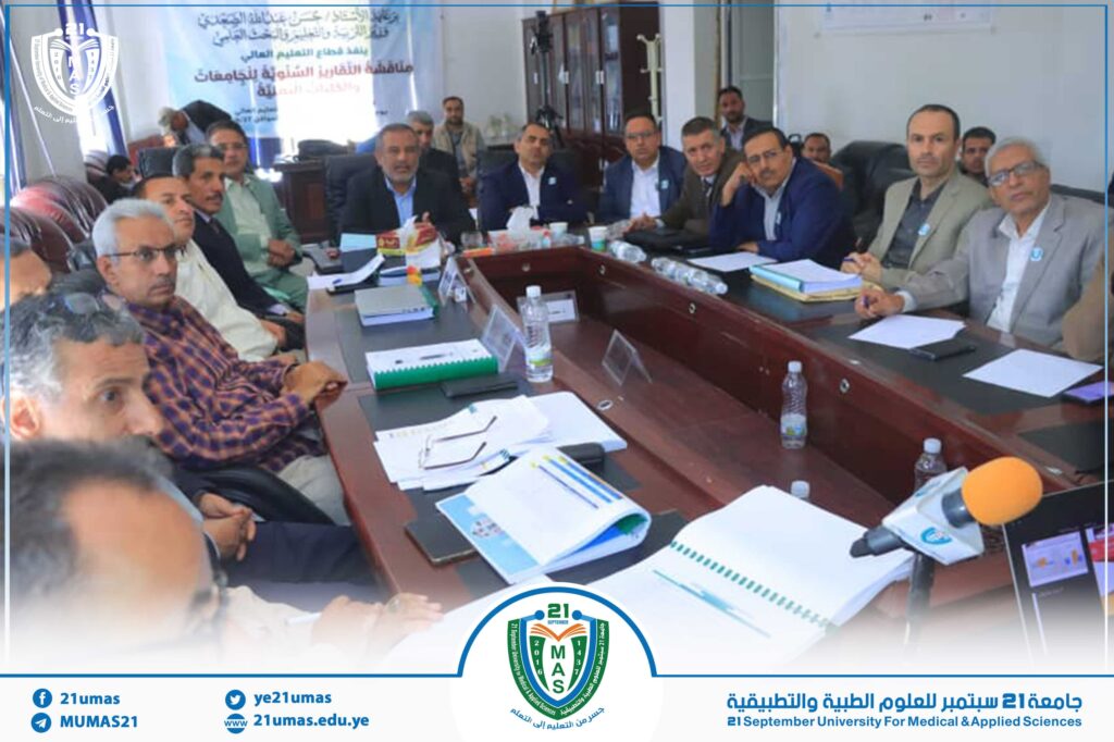 Group of professionals seated around a conference table in a meeting room, with a university banner and logo in the background.