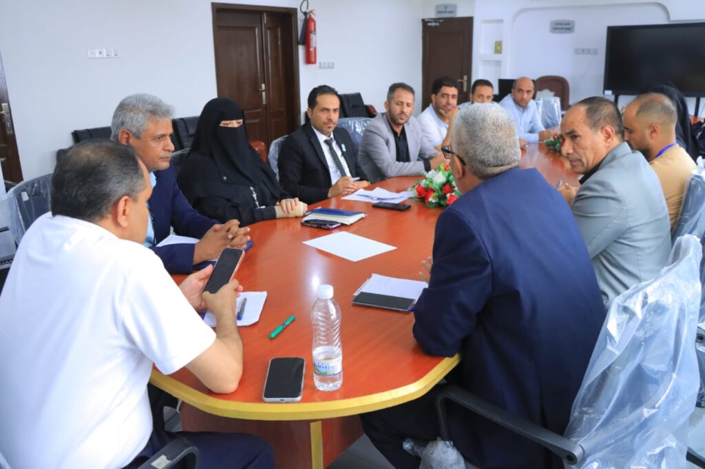 Group of professionals seated around a long conference table in a meeting room, discussing documents.