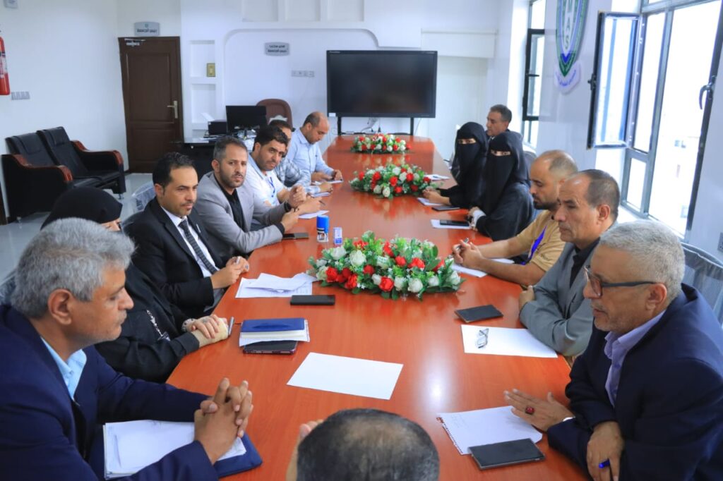 Several professionals seated around a long conference table in a bright meeting room with papers and pens.