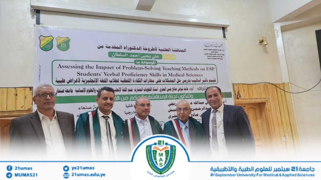 1004053934 - جامعة 21 سبتمبر Group of men in suits and ceremonial robes stand in front of a university banner inside a hall during a formal event.