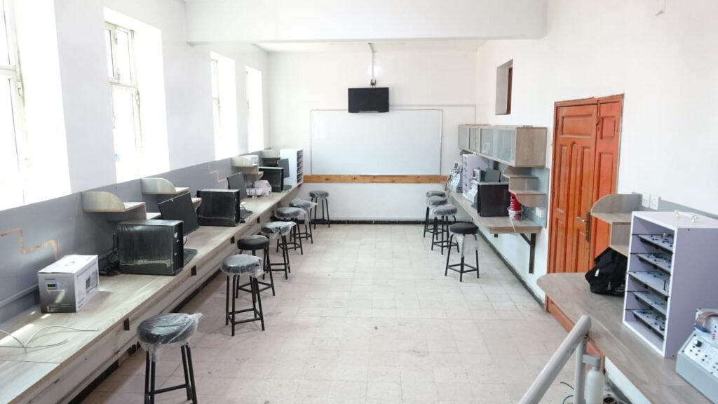 Empty computer lab with row of workstations, stools, and a whiteboard at the front