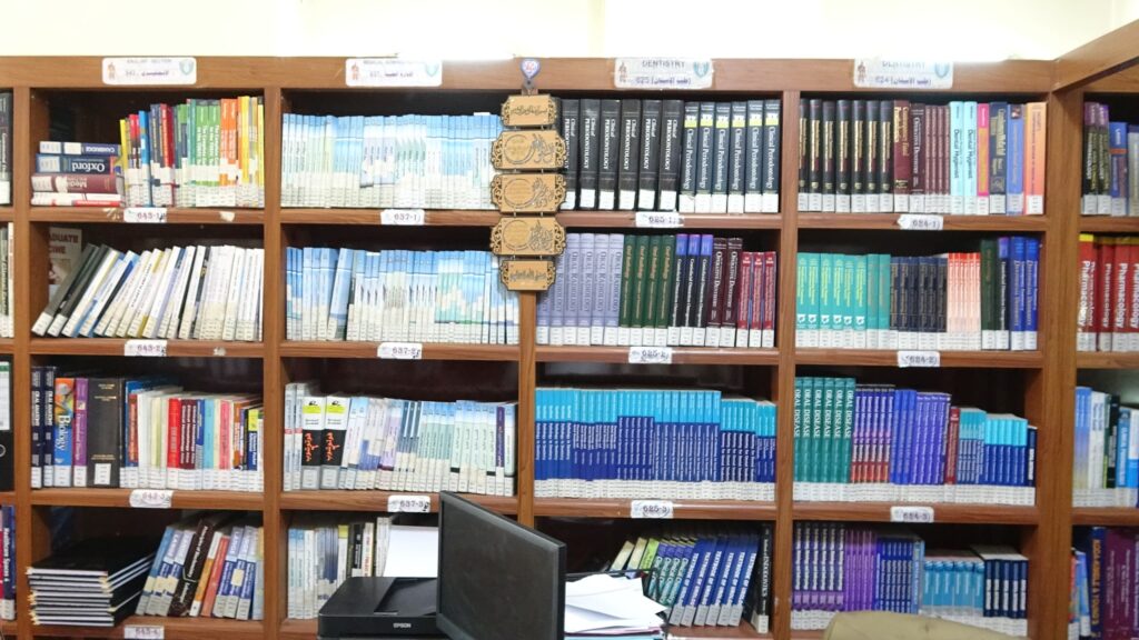 Wooden library shelves filled with medical and science textbooks, organized by category with labeled sections on top.