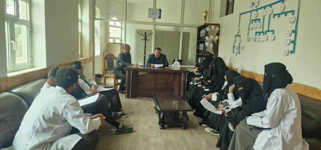 Several people sit around a wooden desk as two men review documents in a bright meeting room.