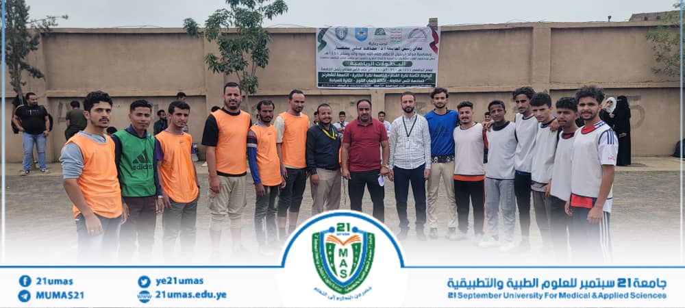 Group of students posing for a photo at an outdoor university event, with a banner and crest in the background.