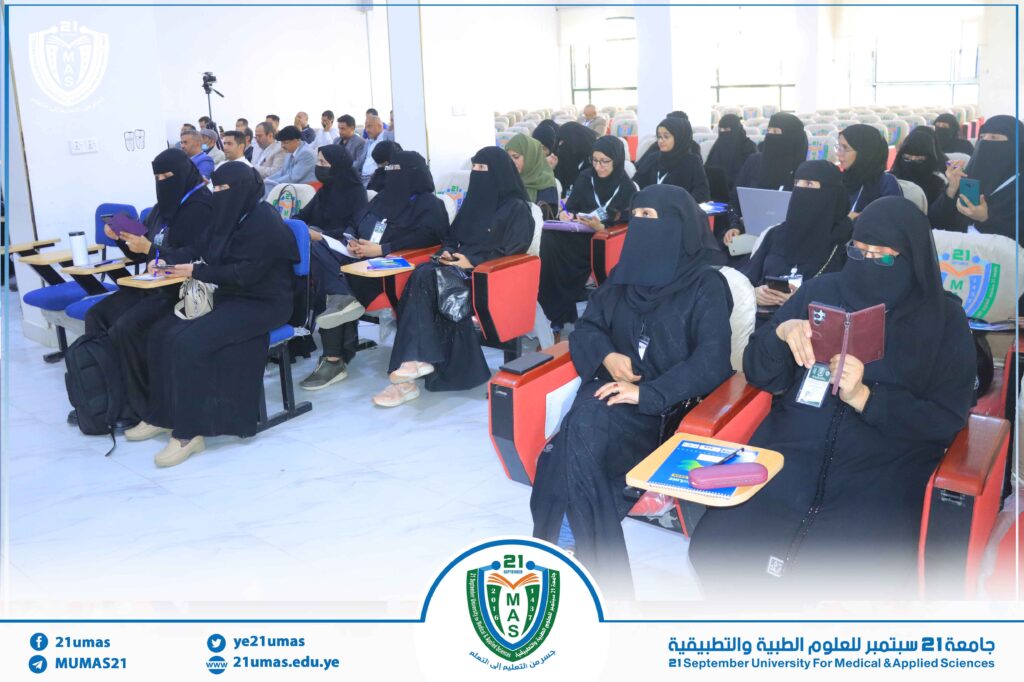 Women in black abayas attend a lecture in a bright auditorium at 21 September University for Medical & Applied Sciences.
