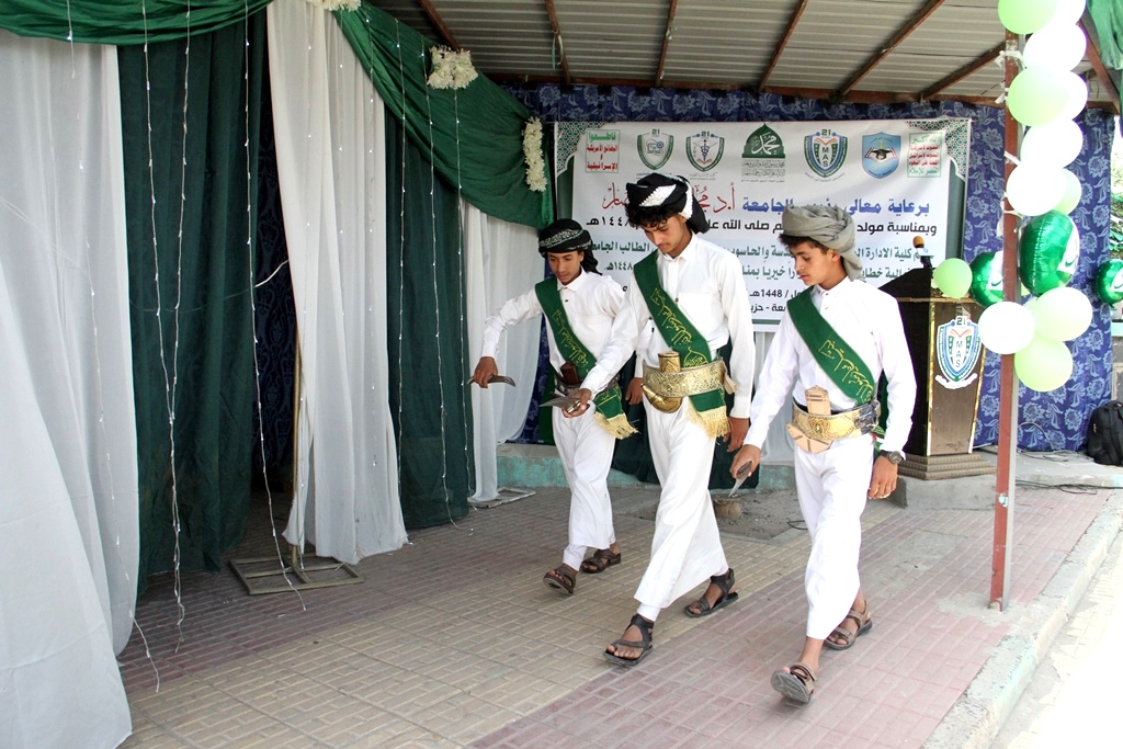 Three young men in white traditional outfits with green sashes walk in a ceremonial event under a decorated canopy.