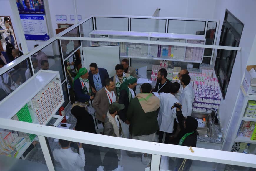 Crowded exhibition booth in a pharmacy setting with clinicians and visitors gathered around a counter of medicines.