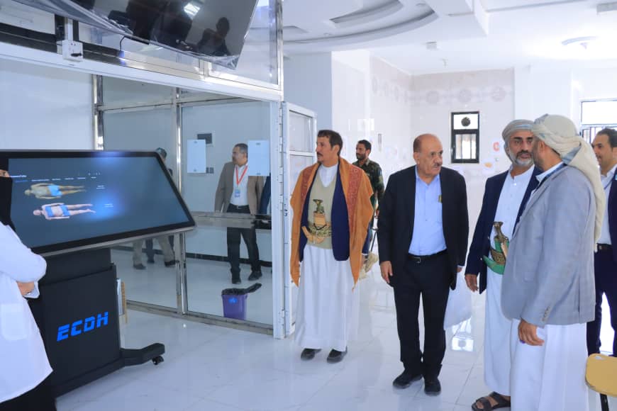 Group of men, some in traditional dress, observing a large touchscreen display in a bright showroom.