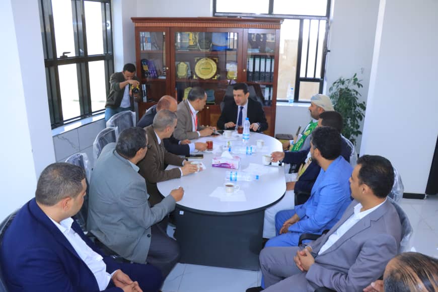 Group of professionals in a meeting around a round table in a bright office, discussing documents and taking notes.