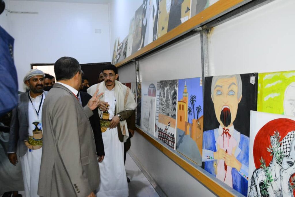 Group of men in traditional clothing viewing student drawings hung along a wall at an art exhibit.