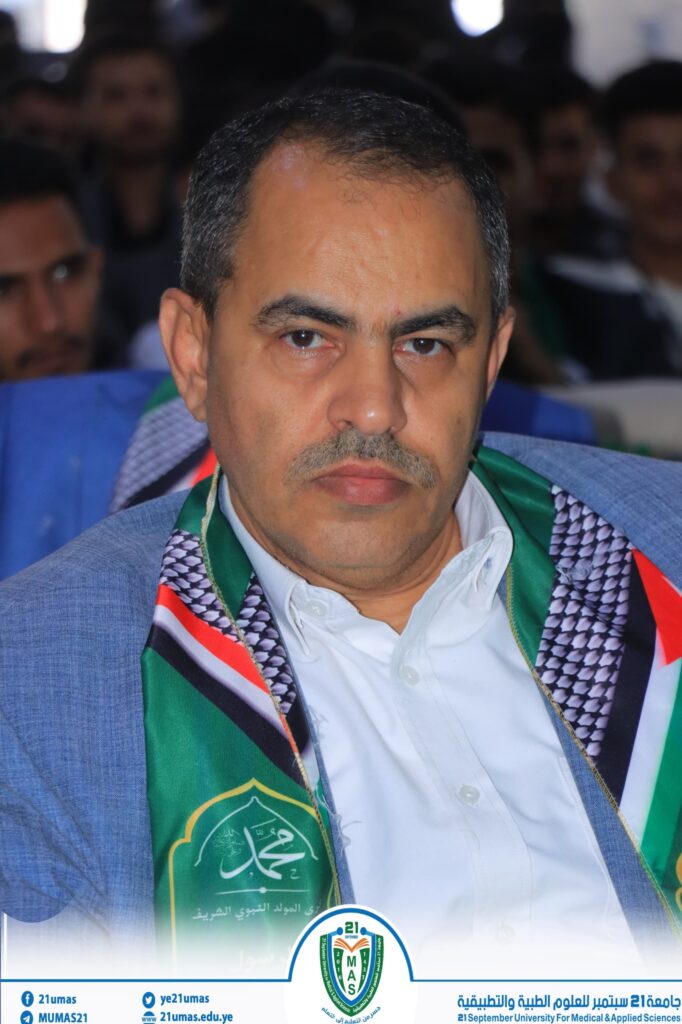Close-up of a man wearing a green ceremonial sash at a formal event, with other attendees blurred in the background.