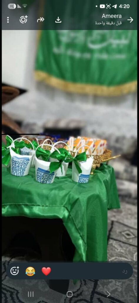 Small white cups with green ribbons arranged on a green tablecloth for a party, with a blurred background on a patterned floor?