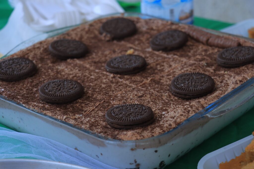 Metal baking tray dusted with cocoa powder, arranged with several chocolate sandwich cookies (Oreos).