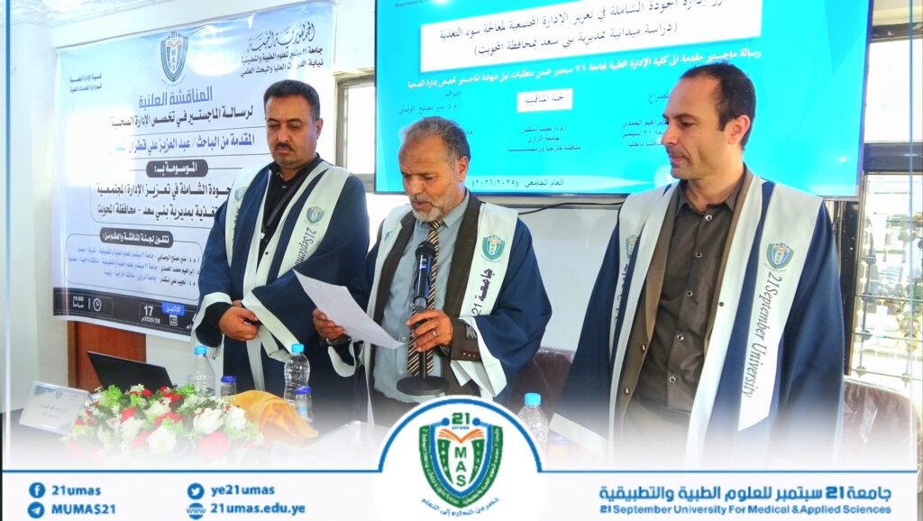 Three men in blue-and-white academic robes stand at a conference table, presenting with a microphone and documents, banners and a blue screen behind them.