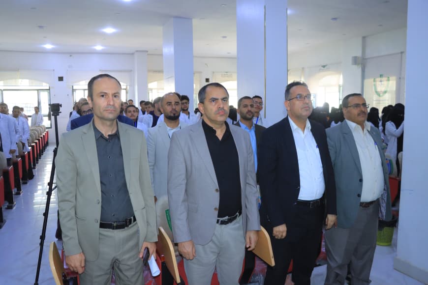 Group of men in suits standing in a conference hall, facing forward during an event.