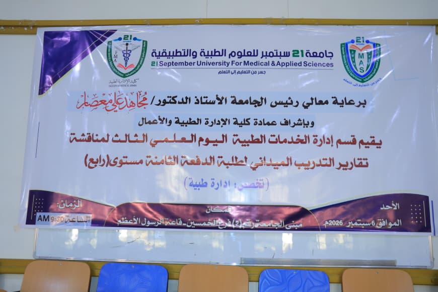 Large banner with university logos and Arabic text announcing a medical sciences university event and a panel discussion, displayed in a hall with blue and orange chairs nearby.