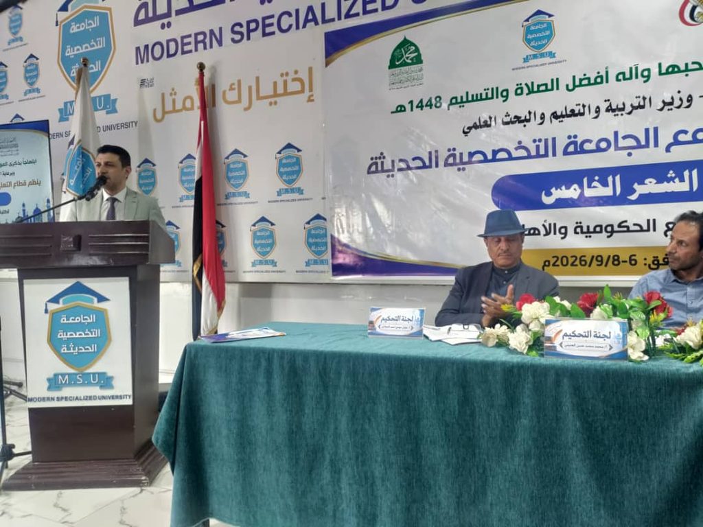 Man speaks at a podium during a university event, with a banner reading Modern Specialized University in the background.