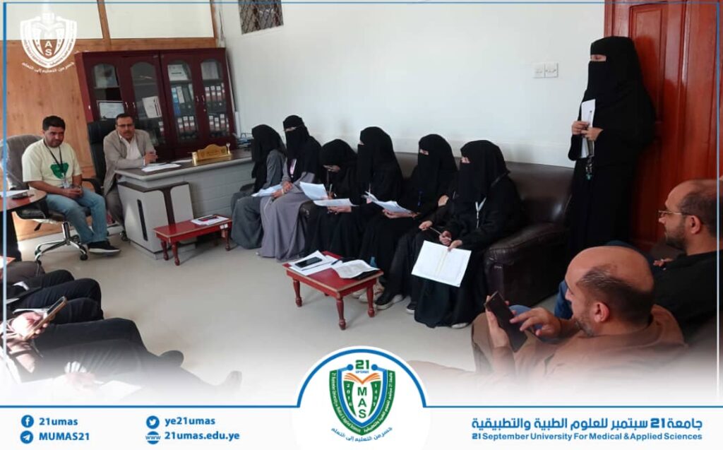 Group of women in black abayas seated along a sofa and chairs in a meeting room, with a man at a desk addressing them.