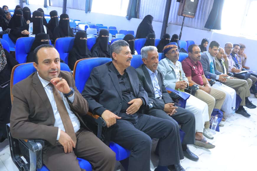 IMG-20260907-WA0046 - جامعة 21 سبتمبر Row of men in suits seated in a conference hall, with women in niqab in the back rows.