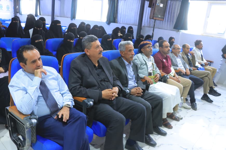 IMG-20260907-WA0060 - جامعة 21 سبتمبر Audience in a conference hall: row of men in suits seated in blue chairs, with women wearing black niqabs in the background.