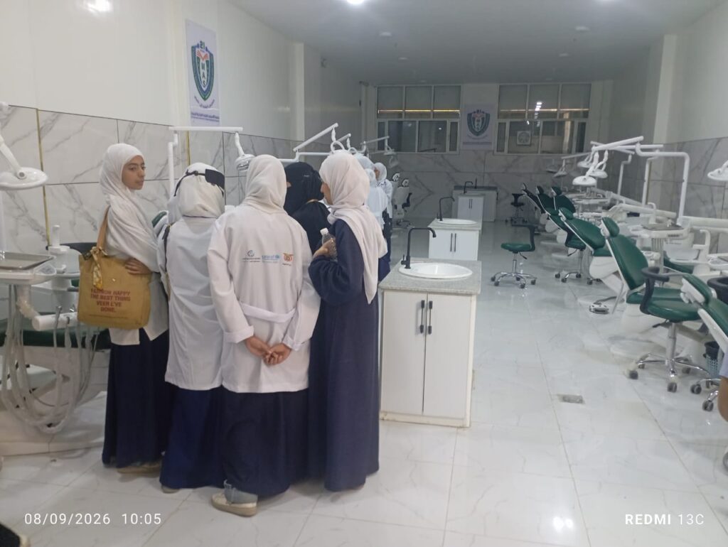 Group of female students in hijabs gathered in a modern dental clinic with dental chairs and equipment in the background.