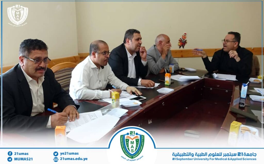Five men in business attire sit around a conference table, reviewing documents in a formal university meeting gesture and discussion scene.