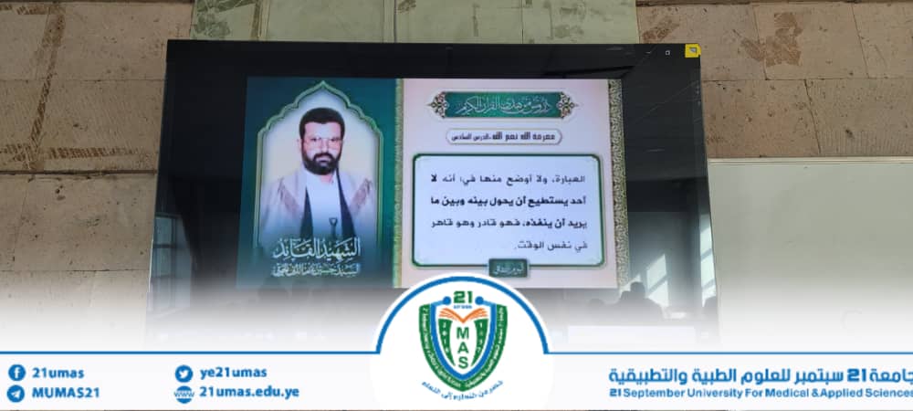 Electronic projection screen showing a portrait of a man and Arabic text slide, with a university banner and crest at the bottom.