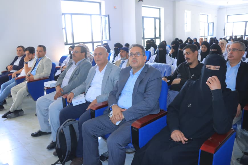 A diverse audience seated in a conference room, listening to a presentation.