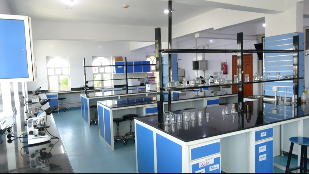 Fully equipped blue-and-white science lab with benches, glassware, and microscopes on the left edge.